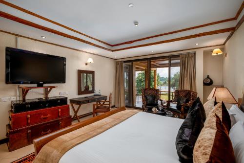 um quarto com uma cama grande e uma televisão de ecrã plano em Chobe Safari Lodge em Kamdini