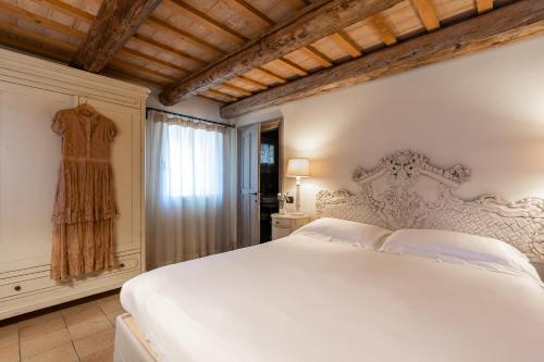 a bedroom with a white bed and a dress in a window at Casina Le Conserve in Cesenatico