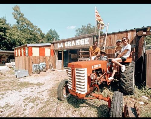 un groupe de personnes assises sur un tracteur devant un bâtiment dans l'établissement Cabane trappeur 4pers à la ferme aventure du perthus, à Le Perthus