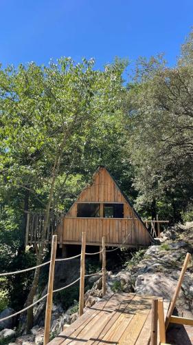 une cabane en bois avec un pont et des arbres dans l'établissement Cabane trappeur 4pers à la ferme aventure du perthus, à Le Perthus
