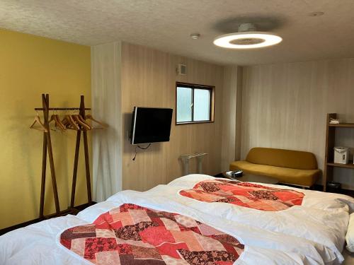 a bedroom with a bed and a couch and a tv at Yodoya in Toyooka
