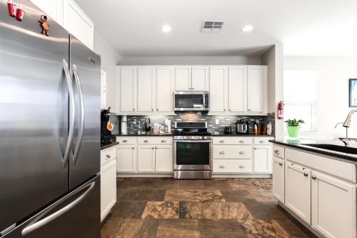 a kitchen with white cabinets and a stainless steel refrigerator at Sunny Vegas Oasis Escape in Las Vegas