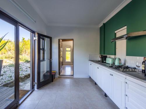 una cocina con armarios blancos y paredes verdes en Cliffside Suites en Plettenberg Bay