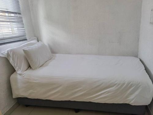 a bed with white sheets and pillows in a room at Beautiful apartment behind Illanga Mall in Mataffin