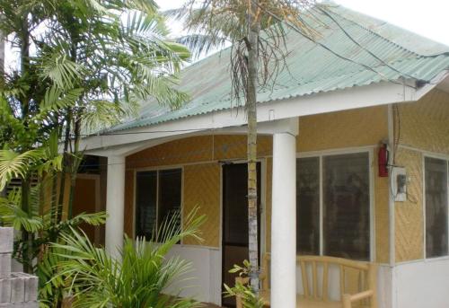 a small yellow house with a green roof at Pabua's Cottages in Mambajao