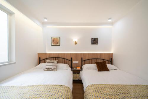 two beds in a room with white walls at Shanghai Downtown Yidu Apartment - 150m walk from Exit 5 of Jiashan Road Metro Station in Shanghai