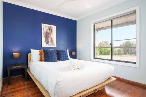 a bedroom with a large white bed with a blue wall at Private Rural Solace at Saje Farm in Cooks Gap in Mudgee