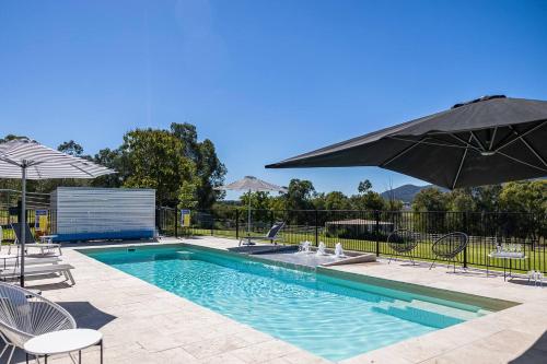 a swimming pool with chairs and an umbrella at 'Bonnie View' A Magnificently Luxurious Retreat in Mudgee