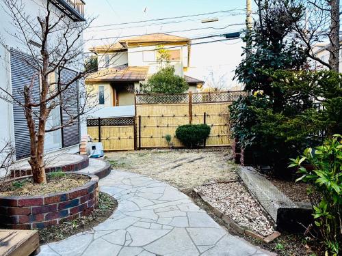 ein Haus mit einem Steinzaun und einem Gehweg in der Unterkunft Nono teru Narita in Narita