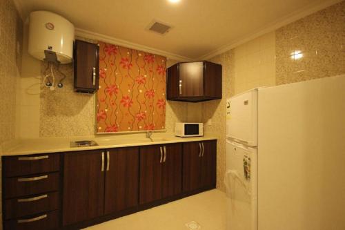 uma cozinha com armários castanhos e um frigorífico branco em اجنحة أروى سويتس الدمام Arwa Suites Dammam em Dammam