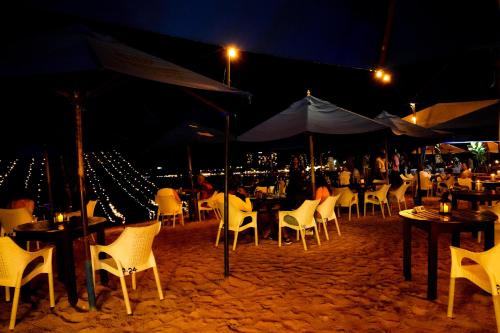 a group of tables with chairs and umbrellas at night at Peacock Beach Hotel Unawatuna in Unawatuna