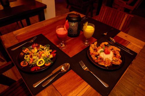 a wooden table with two plates of food and drinks at Peacock Beach Hotel Unawatuna in Unawatuna