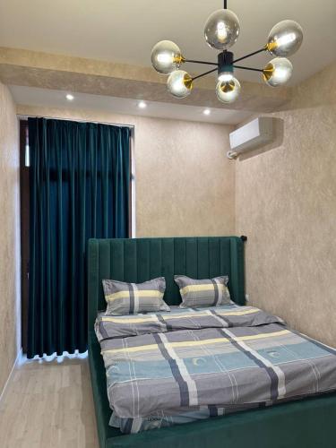 a bedroom with a green bed and a blue curtain at Cozy apartment - City Central in Tashkent