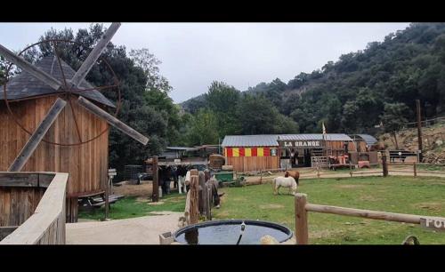 une ferme avec un moulin à vent et des animaux dans un champ dans l'établissement Cabane perché à la ferme aventure du perthus, à Le Perthus