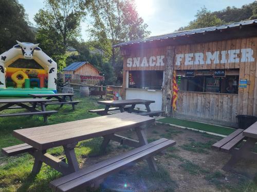 un groupe de tables de pique-nique devant un bâtiment dans l'établissement Cabane perché à la ferme aventure du perthus, à Le Perthus