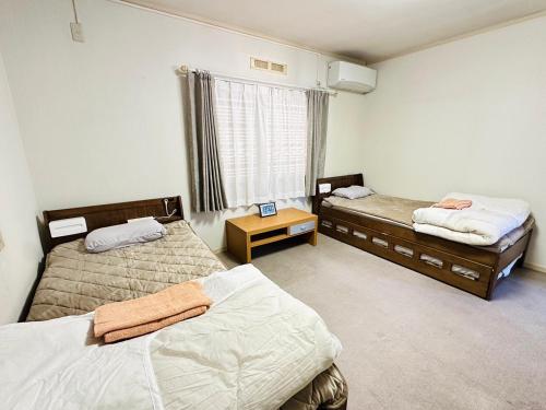 a room with two beds and a window at Nono teru Narita in Narita