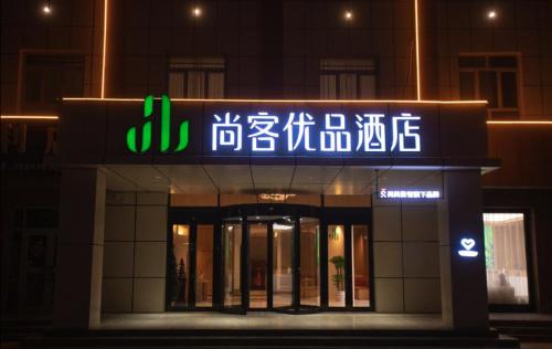 un edificio con un letrero de neón en la parte delantera en Thank Inn Chain Hotel Alar Impression Lanbo Bay Ecological Tourist Park, en Nanfang