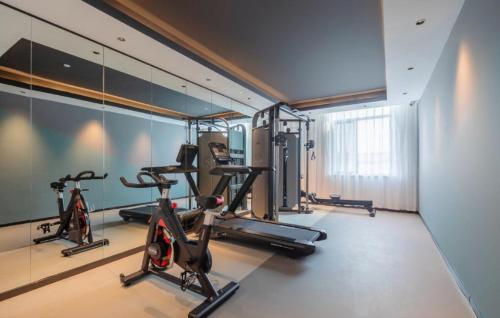 a gym with three exercise bikes and a mirror at Thank Inn Chain Hotel Alar Impression Lanbo Bay Ecological Tourist Park in Nanfang