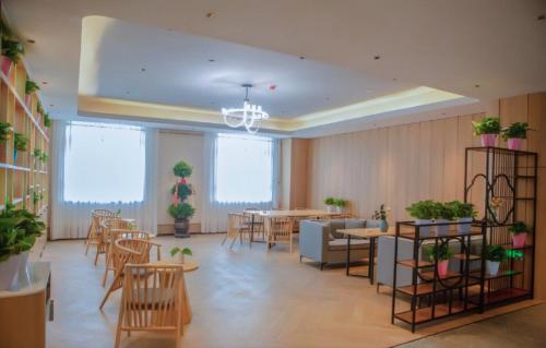 a restaurant with tables and chairs and potted plants at Thank Inn Chain Hotel Alar Impression Lanbo Bay Ecological Tourist Park in Nanfang