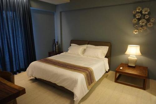 1 dormitorio con 1 cama y 1 mesa con lámpara en Ferringhi Luxury Suite @ By The Sea, en Batu Ferringhi
