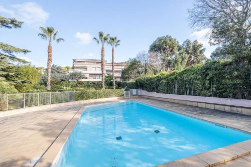 une piscine dans une cour avec des palmiers dans l'établissement Cannes Elegant and Chic 2 Bedroom Apt with Pool, à Cannes