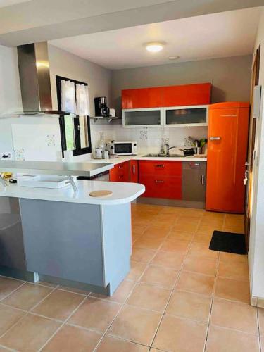 une cuisine avec des armoires rouges et un comptoir blanc dans l'établissement Villa*Piscine*Proche Sarlat, à Proissans