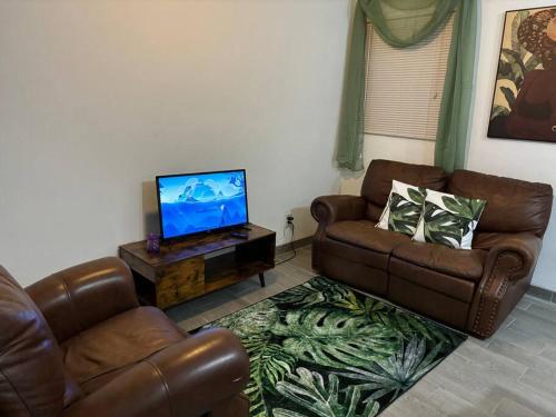 a living room with two leather couches and a flat screen tv at Rae of Sunshine Villas in Hartswell