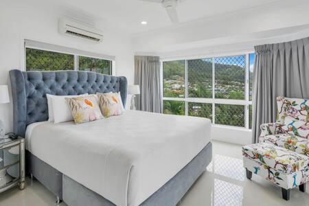 a bedroom with a large white bed and a chair at Mount Sheridan home with Breath taking views in Cairns