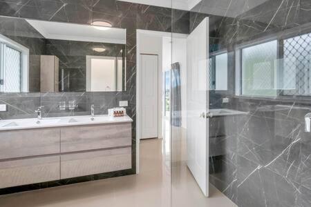 a bathroom with a tub and a sink and a mirror at Mount Sheridan home with Breath taking views in Cairns