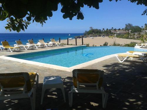 a swimming pool with lounge chairs and the beach at Los Balcones in Sosúa
