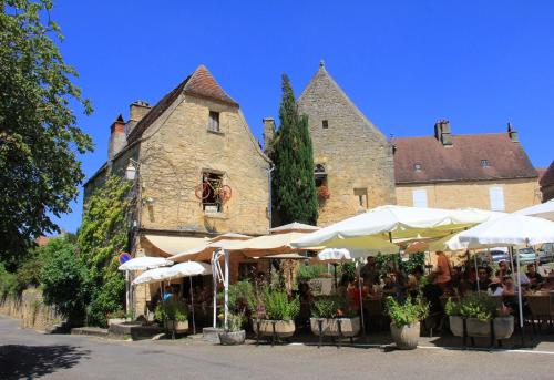 a building with tables and umbrellas in front of it at Le Coeur de Domme in Domme