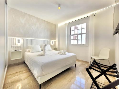 una camera da letto bianca con un letto bianco e una sedia di The Stylish Apartment a Puerto de la Cruz