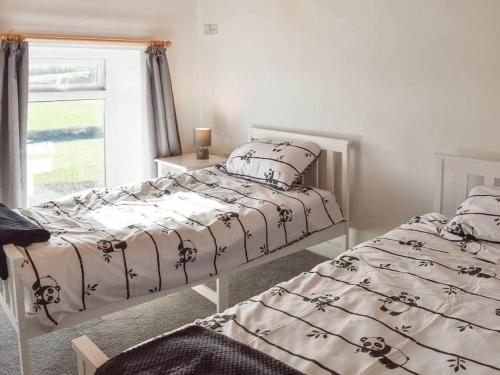 two twin beds in a bedroom with a window at Bron Haul, Mountain Views in Brynteg