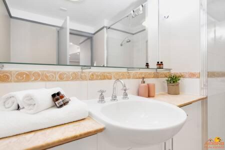 uma casa de banho branca com um lavatório e um espelho em The heart of Cairns City with panoramic views em Cairns