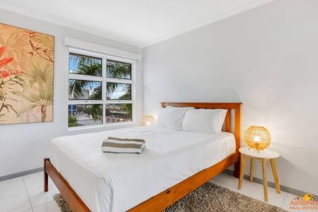 a white bedroom with a bed and a window at The heart of Cairns City with panoramic views in Cairns