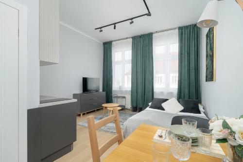 een woonkamer met een bed en een tafel bij Stylish Grey Apartments with a City View in Poznań by Renters in Poznań