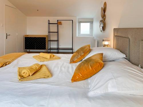 uma grande cama branca com almofadas laranja em Échappée de la Loire - Jardin - Parking - 3 chamb. em Divatte sur Loire