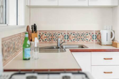 a kitchen with a sink and a bottle on the counter at Edge Hill - spectacular views of the city and sea in Edge Hill