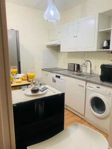 eine Küche mit einer Spüle und einer Waschmaschine in der Unterkunft Appartement calme et chaleureux proche de Paris in Courbevoie