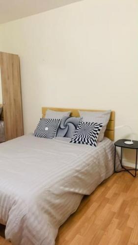 ein Schlafzimmer mit einem weißen Bett mit Kissen darauf in der Unterkunft Appartement calme et chaleureux proche de Paris in Courbevoie