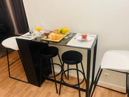 einen Tisch mit einem Teller Essen und zwei Barhockern in der Unterkunft Appartement calme et chaleureux proche de Paris in Courbevoie