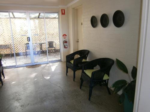 a room with two chairs and a table and windows at Kellys Motel Oakey in Oakey