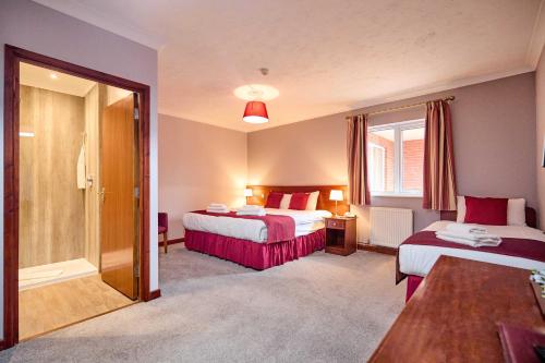 a hotel room with two beds and a window at Wensum Valley Hotel Golf and Country Club in Norwich