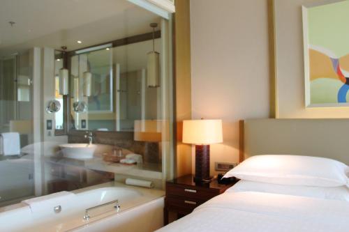 a bedroom with a bed and a tub and a lamp at Sheraton Bailuhu Resort, Huizhou in Huizhou