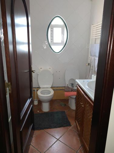 y baño con aseo, lavabo y espejo. en Belo Jardim Villa, en Samora Correia