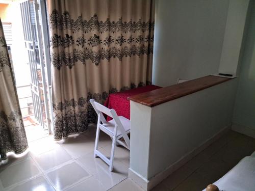 a room with a desk and a chair and a curtain at Harod Suites in Kampala