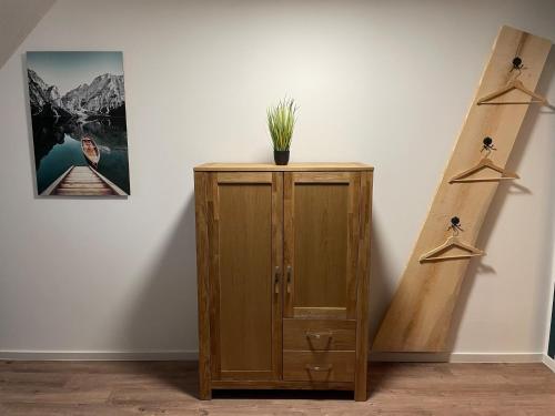 a wooden cabinet with a plant on it next to a wall at Ferienwohnung Haus Peters "De Groote" in Marschkamp
