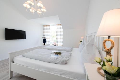a white bedroom with two beds and a tv at Schiff in Gelting