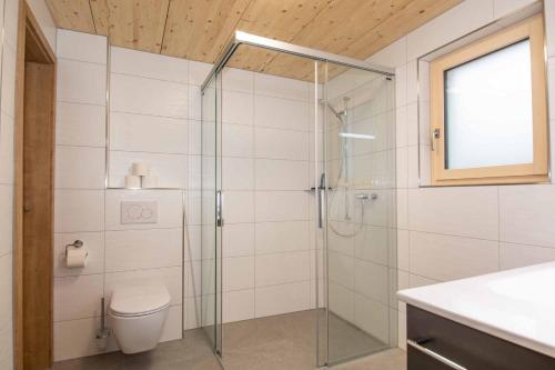 uma casa de banho com uma cabina de duche em vidro e um WC. em Ferienchalet Sonne em Adelboden