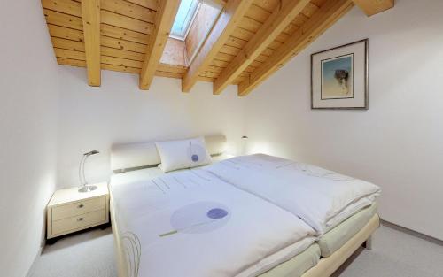 1 dormitorio con cama blanca y techo de madera en Sur Crasta, en Celerina